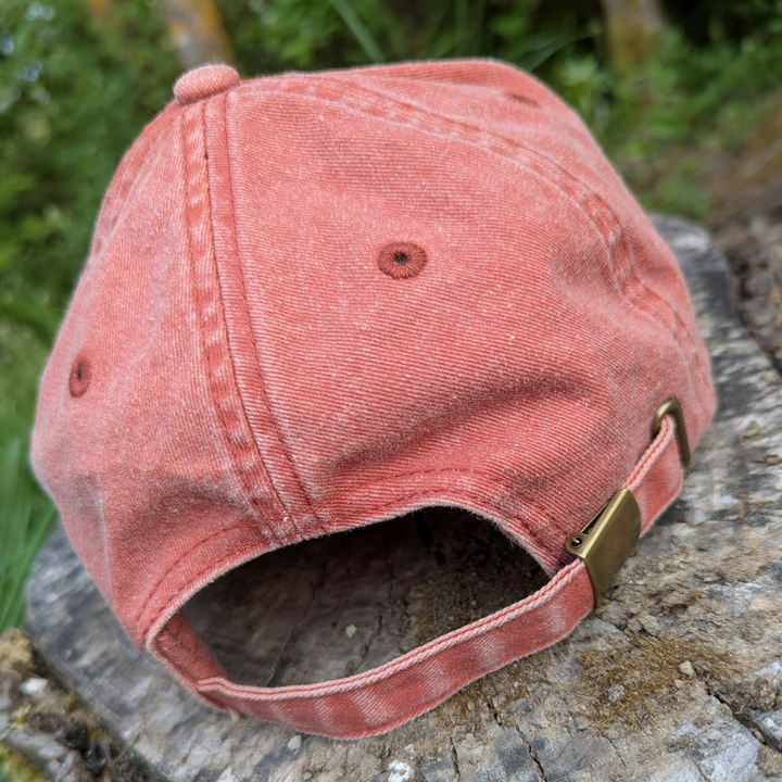 Rückseite einer roten Vintage-Cap mit Messingverschluss und verstellbarem Riemen im Used-Look.