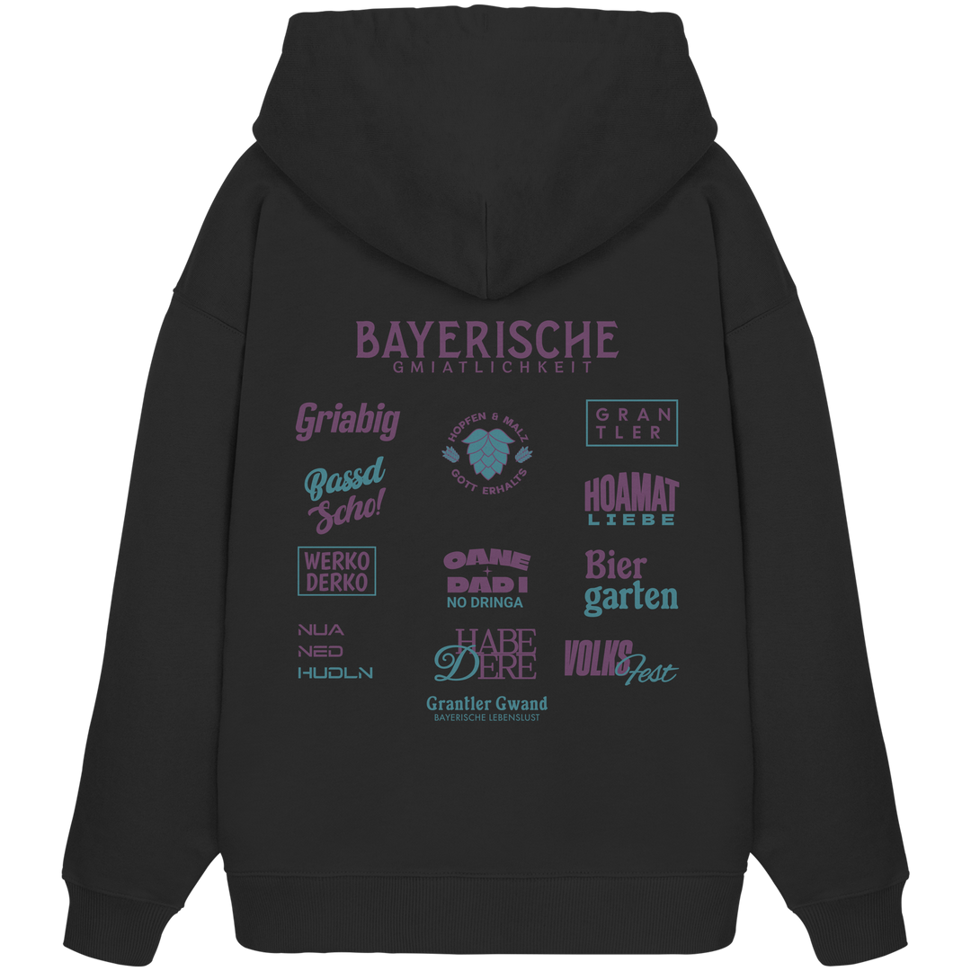Schwarzer Oversize Hoodie mit großem lila Backprint „Bayerische Gmiatlichkeit“ und bayerischen Begriffen wie Hoamatliebe, Biergarten, Volksfest, Grantler, Hopfen &amp; Malz und Griabig. Unisex Premium-Hoodie aus Bio-Baumwolle im modernen Streetwear-Style. Designed und bedruckt in Bayern von Grantler Gwand.