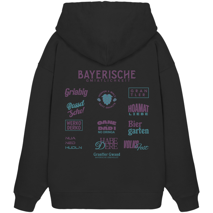 Schwarzer Oversize Hoodie mit großem lila Backprint „Bayerische Gmiatlichkeit“ und bayerischen Begriffen wie Hoamatliebe, Biergarten, Volksfest, Grantler, Hopfen &amp; Malz und Griabig. Unisex Premium-Hoodie aus Bio-Baumwolle im modernen Streetwear-Style. Designed und bedruckt in Bayern von Grantler Gwand.