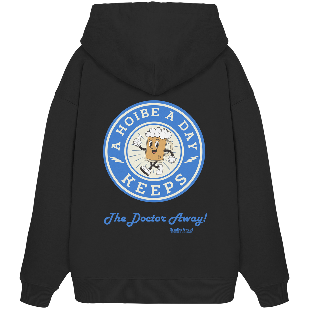 Schwarzer Oversize-Hoodie mit großem Backprint „A Hoibe A Day – Keeps the Doctor Away“ im Retro-Bierdeckel-Design mit blauen Akzenten. Extra schwerer Premium-Hoodie aus Bio-Baumwolle für Biergarten, Volksfest und bayerische Streetwear. Designed und bedruckt in Bayern von Grantler Gwand.