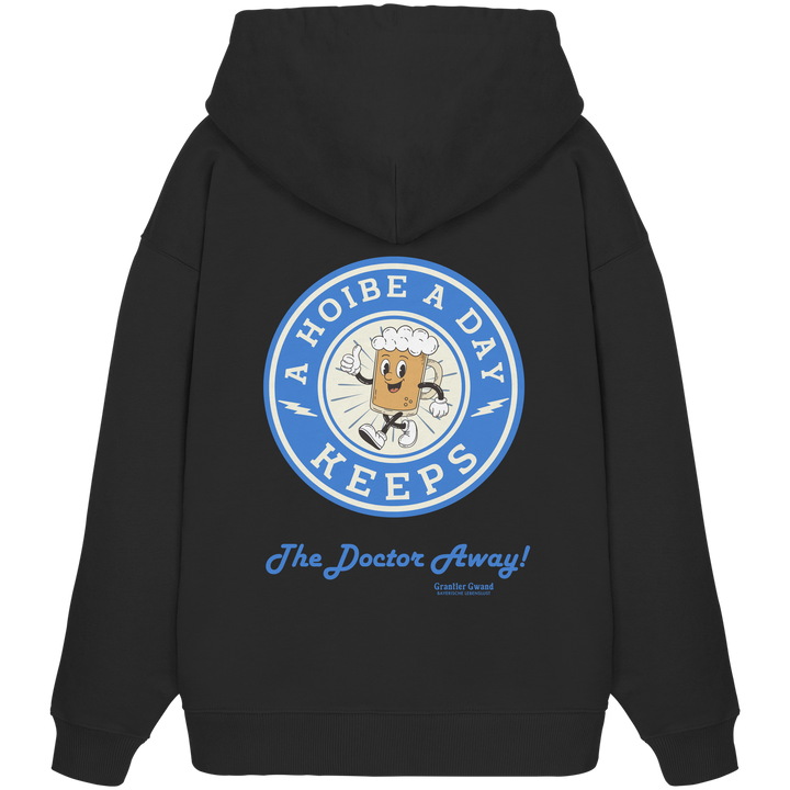 Schwarzer Oversize-Hoodie mit großem Backprint „A Hoibe A Day – Keeps the Doctor Away“ im Retro-Bierdeckel-Design mit blauen Akzenten. Extra schwerer Premium-Hoodie aus Bio-Baumwolle für Biergarten, Volksfest und bayerische Streetwear. Designed und bedruckt in Bayern von Grantler Gwand.