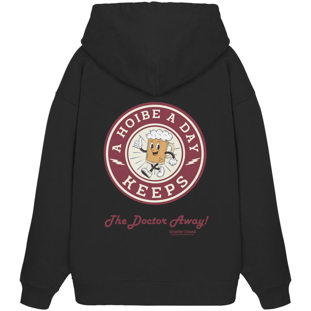 Schwarzer Oversize-Hoodie mit großem Backprint „A Hoibe A Day – Keeps the Doctor Away“ im Retro-Bierdeckel-Design. Extra schwerer Premium-Hoodie aus Bio-Baumwolle für Biergarten, Volksfest und bayerische Streetwear. Designed und bedruckt in Bayern von Grantler Gwand.
