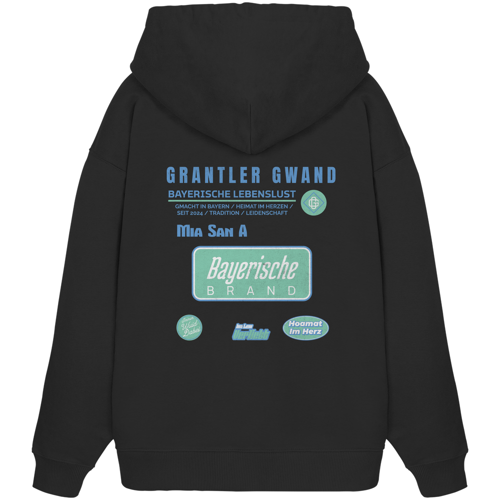 Schwarzer Oversize Hoodie mit großem Grantler Gwand Backprint, blau-grünem „Bayerische Brand“-Schriftzug und moderner bayerischer Streetwear-Grafik.