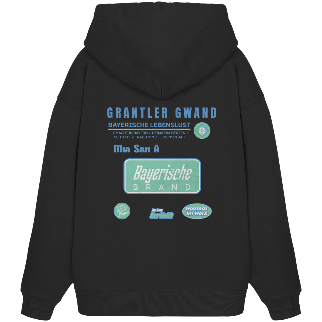 Schwarzer Oversize Hoodie mit großem Grantler Gwand Backprint, blau-grünem „Bayerische Brand“-Schriftzug und moderner bayerischer Streetwear-Grafik.