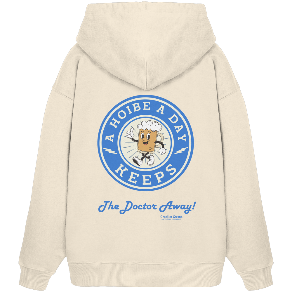 Beiger Oversize-Hoodie mit großem Backprint „A Hoibe A Day – Keeps the Doctor Away“ im Retro-Bierdeckel-Design mit blauen Akzenten. Extra schwerer Premium-Hoodie aus Bio-Baumwolle für Biergarten, Volksfest und bayerische Streetwear. Designed und bedruckt in Bayern von Grantler Gwand.