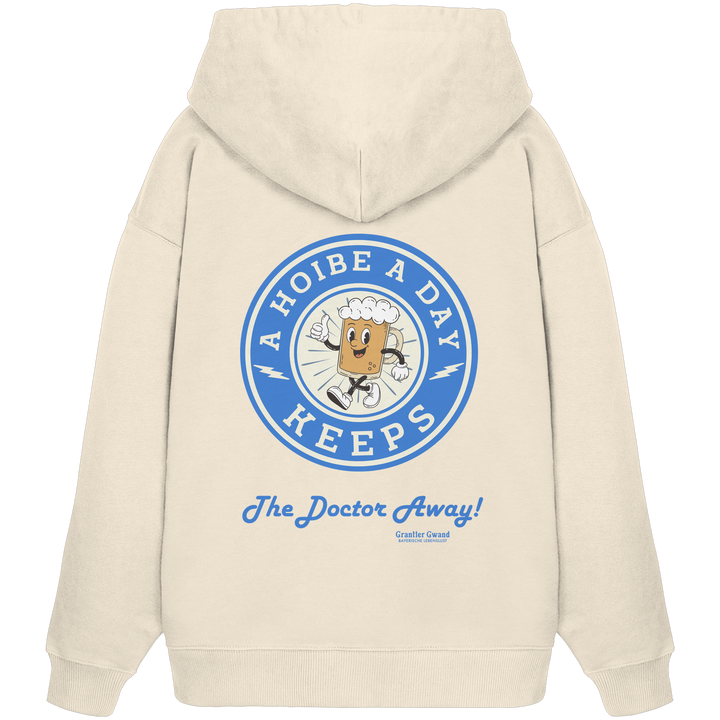 Beiger Oversize-Hoodie mit großem Backprint „A Hoibe A Day – Keeps the Doctor Away“ im Retro-Bierdeckel-Design mit blauen Akzenten. Extra schwerer Premium-Hoodie aus Bio-Baumwolle für Biergarten, Volksfest und bayerische Streetwear. Designed und bedruckt in Bayern von Grantler Gwand.