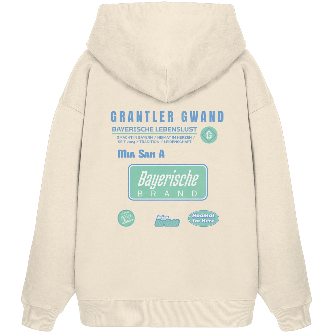 Naturfarbener Oversize Hoodie mit großem Grantler Gwand Backprint, blau-grünem „Bayerische Brand“-Schriftzug und moderner bayerischer Streetwear-Grafik.