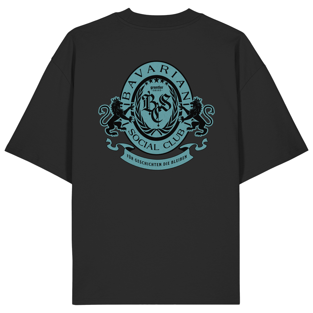 schwarzes Oversize T-Shirt mit großem mintfarben-schwarzem Bavarian Social Club Wappen auf dem Rücken, verziert mit zwei Löwen, Lorbeerkranz und dem Schriftzug „Für Geschichten die bleiben“.