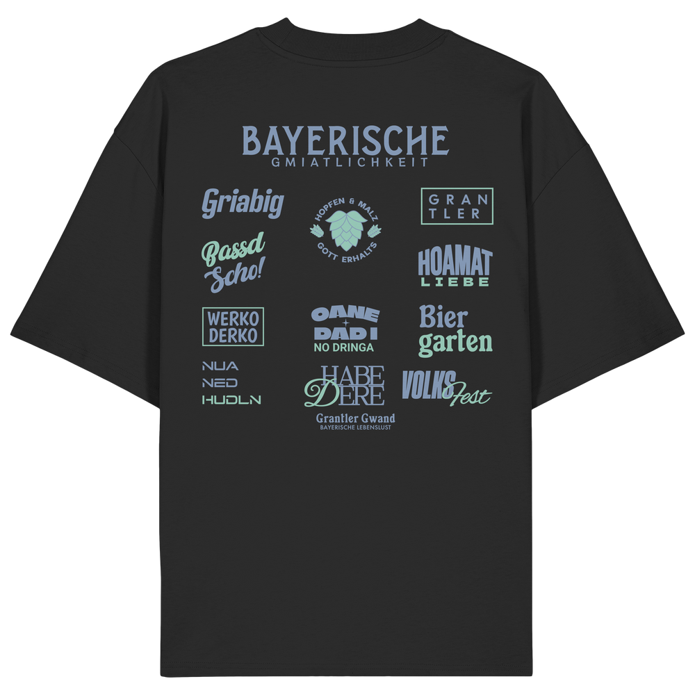 Schwarzes Bayerische Gmiatlichkeit Oversize Shirt mit großem grünem Backprint und bayerischen Begriffen wie Hoamatliebe, Biergarten, Volksfest, Grantler, Hopfen & Malz und Griabig. Unisex Heavy Oversized T-Shirt aus Bio-Baumwolle im modernen Streetwear-Look. Designed und bedruckt in Bayern von Grantler Gwand.