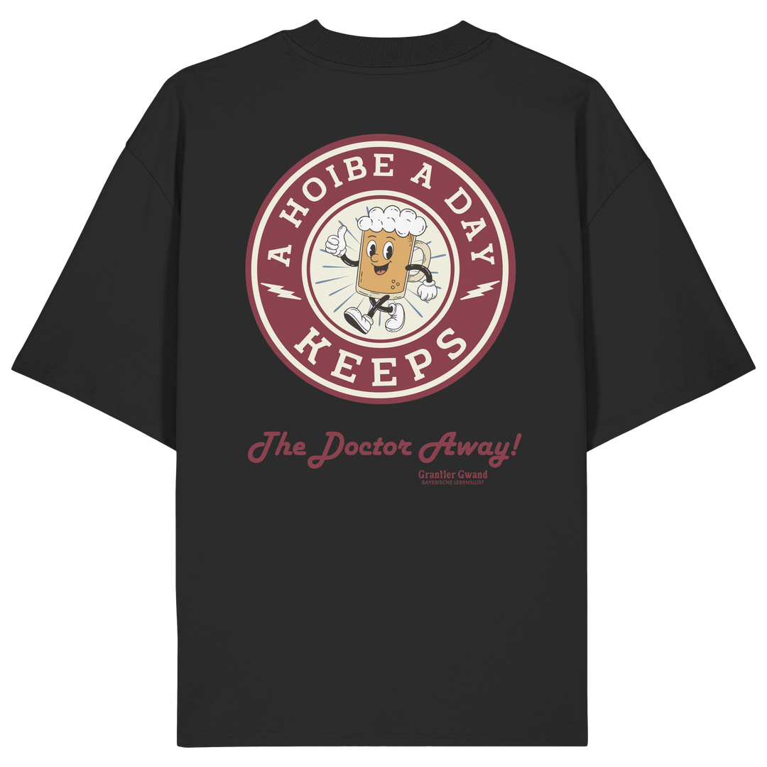 Schwarzes Oversize-T-Shirt mit großem Backprint „A Hoibe A Day – Keeps the Doctor Away“ im Retro-Bierdeckel-Design. Schweres Premium-Shirt aus 100 % Bio-Baumwolle für Biergarten, Volksfest und bayerische Streetwear. Designed und bedruckt in Bayern von Grantler Gwand.