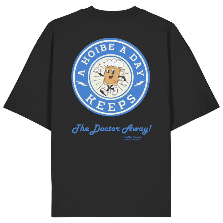Oversize Unisex-Shirt in Schwarz mit großem Backprint „A Hoibe A Day – Keeps the Doctor Away“ im Retro-Bierdeckel-Design mit blauen Akzenten. Modernes bayerisches Streetwear-Shirt für Biergarten, Volksfest und gesellige Momente. Designed und bedruckt in Bayern von Grantler Gwand.
