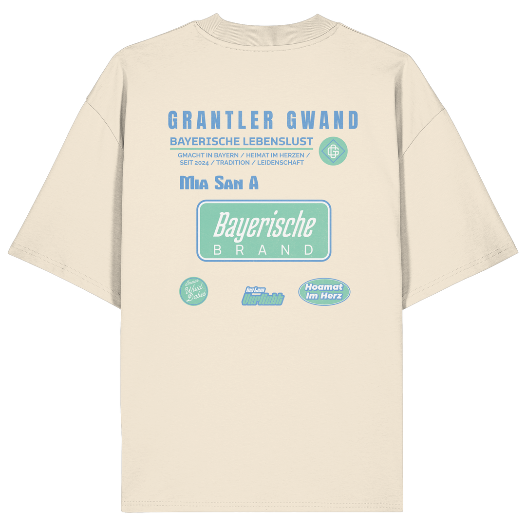 Naturfarbenes Oversize T-Shirt mit großem Grantler Gwand Backprint in Blau und Mintgrün sowie dem Schriftzug „Bayerische Brand“ im modernen Streetwear-Design.