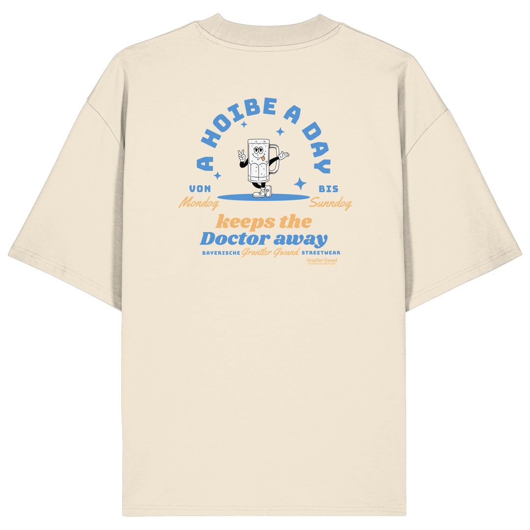 Cremefarbenes Oversize T-Shirt von Grantler Gwand mit Backprint „A Hoibe a Day keeps the Doctor away“, Bierkrug-Maskottchen im Retro-Design und hellblauen Details – bayerisches Streetwear Shirt aus Bio-Baumwolle.