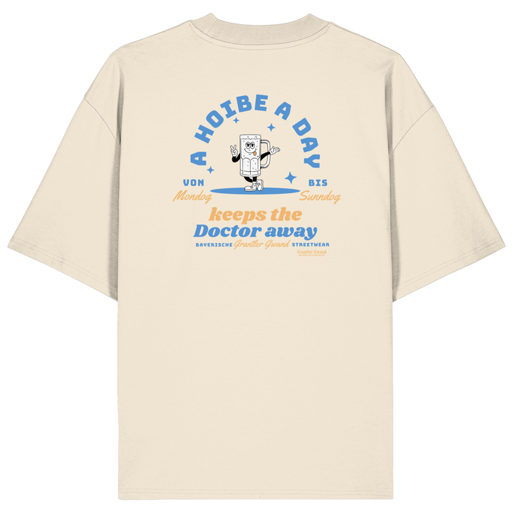 Cremefarbenes Oversize T-Shirt von Grantler Gwand mit Backprint „A Hoibe a Day keeps the Doctor away“, Bierkrug-Maskottchen im Retro-Design und hellblauen Details – bayerisches Streetwear Shirt aus Bio-Baumwolle.