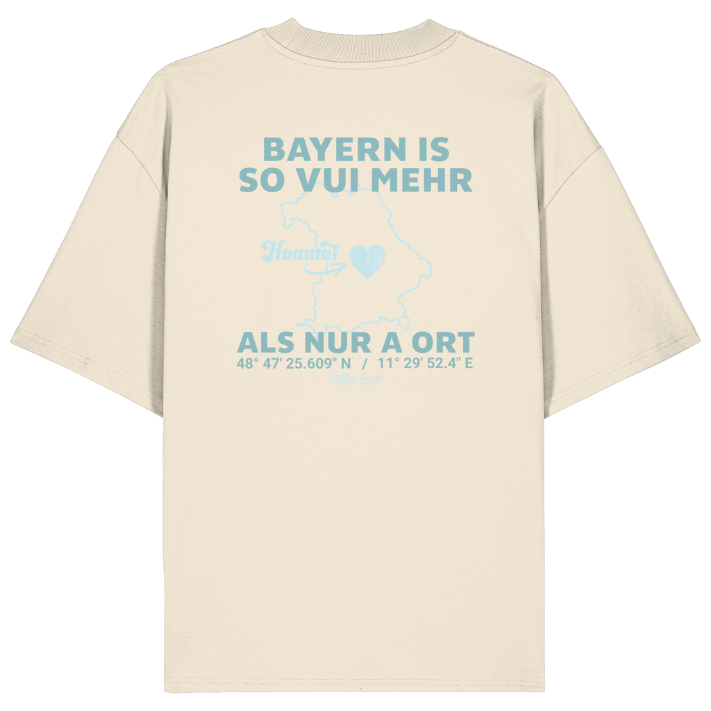 Cremefarbenes Oversize T-Shirt von Grantler Gwand mit grünem Backprint „Bayern is so vui mehr als nur a Ort“ und Bayern-Silhouette – bayerisches Streetwear Shirt aus Bio-Baumwolle.