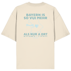 Cremefarbenes Oversize T-Shirt von Grantler Gwand mit grünem Backprint „Bayern is so vui mehr als nur a Ort“ und Bayern-Silhouette – bayerisches Streetwear Shirt aus Bio-Baumwolle.