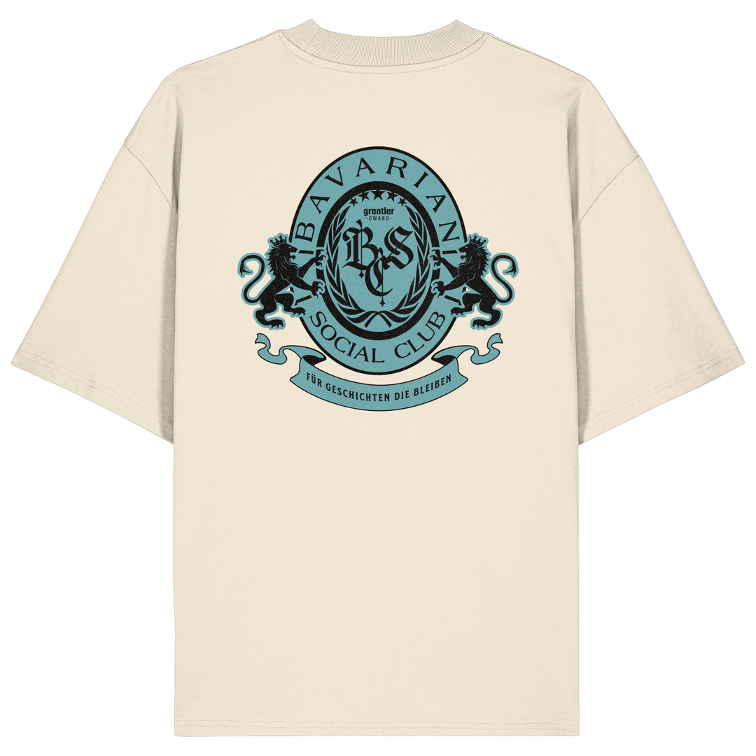 naturfarbenes Oversize T-Shirt mit großem mintfarben-schwarzem Bavarian Social Club Wappen auf dem Rücken, verziert mit zwei Löwen, Lorbeerkranz und dem Schriftzug „Für Geschichten die bleiben“.