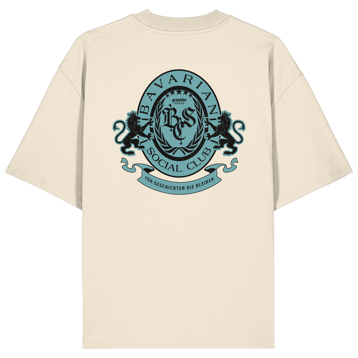 naturfarbenes Oversize T-Shirt mit großem mintfarben-schwarzem Bavarian Social Club Wappen auf dem Rücken, verziert mit zwei Löwen, Lorbeerkranz und dem Schriftzug „Für Geschichten die bleiben“.