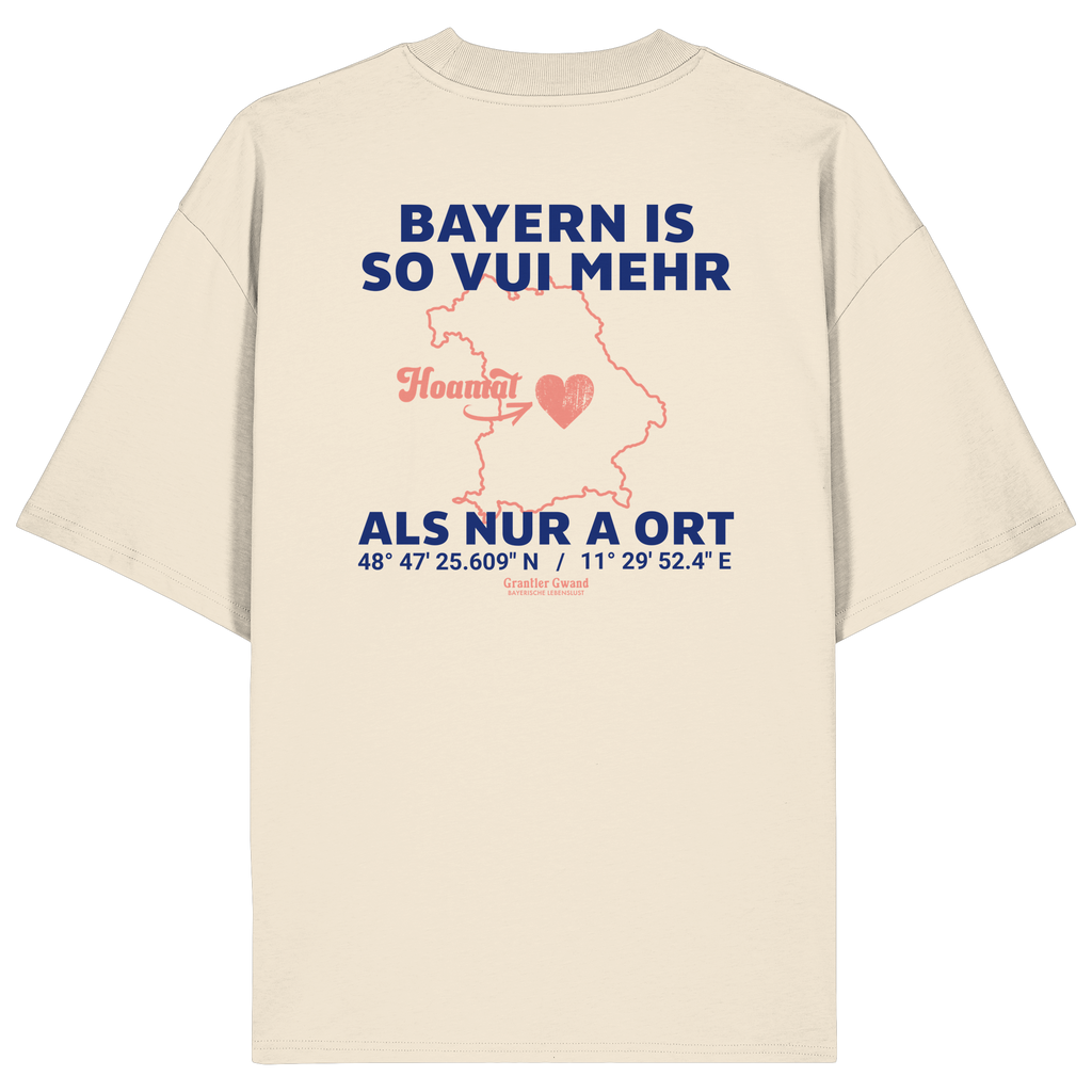 Cremefarbenes Oversize T-Shirt von Grantler Gwand mit blauem Backprint „Bayern is so vui mehr als nur a Ort“, Herzsymbol und Bayern-Silhouette – bayerisches Streetwear Shirt aus Bio-Baumwolle.