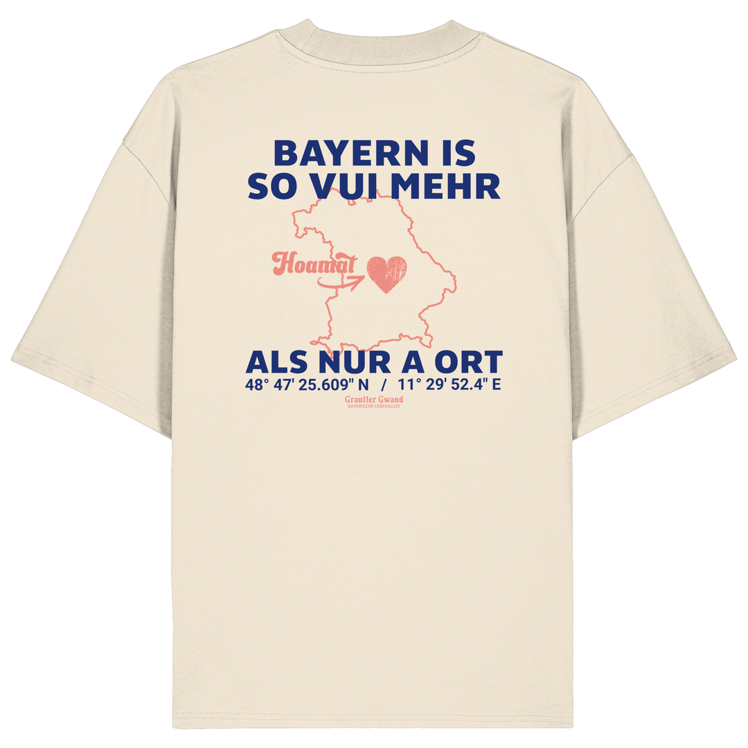 Cremefarbenes Oversize T-Shirt von Grantler Gwand mit blauem Backprint „Bayern is so vui mehr als nur a Ort“, Herzsymbol und Bayern-Silhouette – bayerisches Streetwear Shirt aus Bio-Baumwolle.
