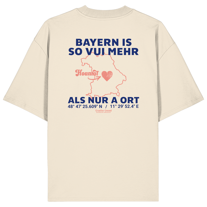 Cremefarbenes Oversize T-Shirt von Grantler Gwand mit blauem Backprint „Bayern is so vui mehr als nur a Ort“, Herzsymbol und Bayern-Silhouette – bayerisches Streetwear Shirt aus Bio-Baumwolle.