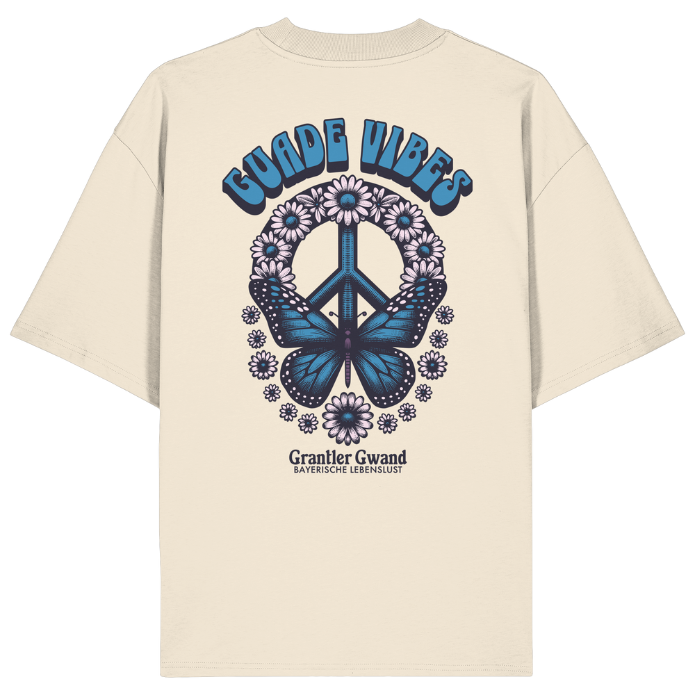 Cremefarbenes Unisex Oversize Shirt mit großem Backprint aus Peace-Zeichen, Schmetterling und Blumen sowie „Guade Vibes“ Schriftzug – hochwertiges Bio-Baumwoll Streetwear T-Shirt im bayerischen Style von Grantler Gwand.