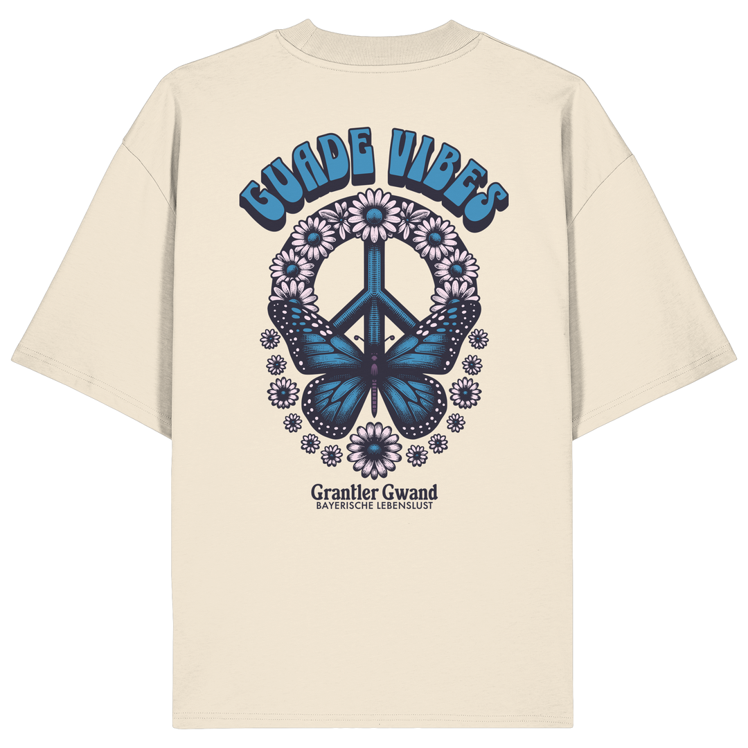Cremefarbenes Unisex Oversize Shirt mit großem Backprint aus Peace-Zeichen, Schmetterling und Blumen sowie „Guade Vibes“ Schriftzug – hochwertiges Bio-Baumwoll Streetwear T-Shirt im bayerischen Style von Grantler Gwand.