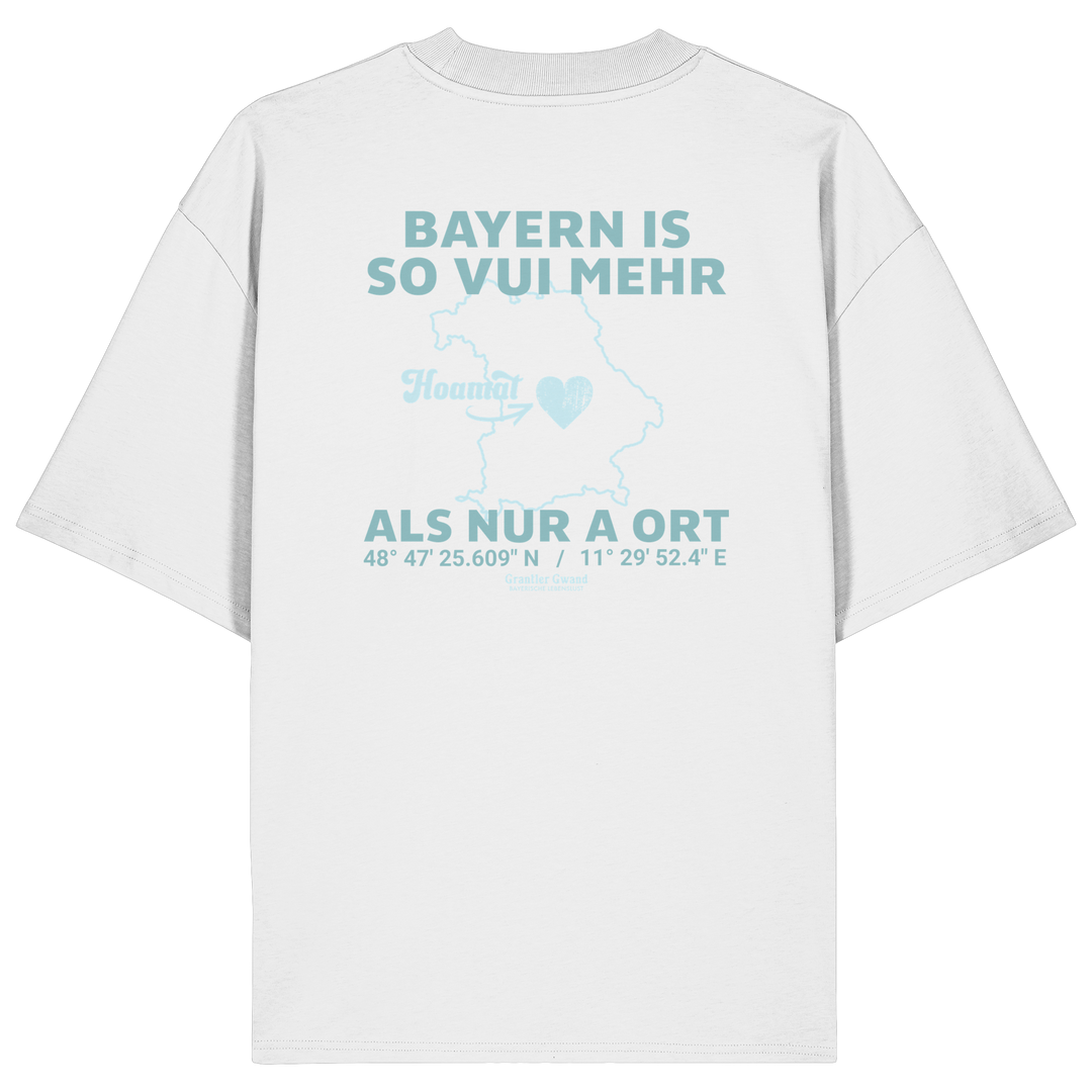 Weißes Oversize T-Shirt von Grantler Gwand mit grünem Backprint „Bayern is so vui mehr als nur a Ort“ und Bayern-Silhouette – bayerisches Streetwear Shirt aus Bio-Baumwolle.