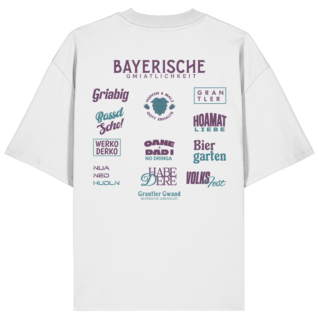 Weißes Oversize-Shirt mit großem lila Backprint „Bayerische Gmiatlichkeit“ und typischen bayerischen Begriffen wie Hoamatliebe, Biergarten, Volksfest, Grantler, Hopfen &amp; Malz und Griabig. Unisex Premium-Shirt aus Bio-Baumwolle im modernen Streetwear-Style. Designed und bedruckt in Bayern von Grantler Gwand.