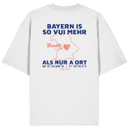 Weißes Oversize T-Shirt von Grantler Gwand mit blauem Backprint „Bayern is so vui mehr als nur a Ort“, Herzsymbol und Bayern-Silhouette – bayerisches Streetwear Shirt aus Bio-Baumwolle.