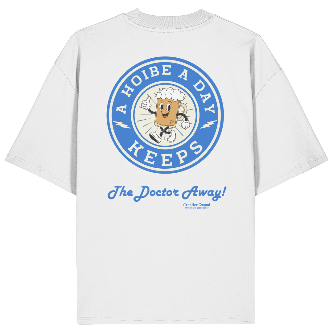 Oversize Unisex-Shirt in Weiß mit großem Backprint „A Hoibe A Day – Keeps the Doctor Away“ im Retro-Bierdeckel-Design mit blauen Akzenten. Modernes bayerisches Streetwear-Shirt für Biergarten, Volksfest und gesellige Momente. Designed und bedruckt in Bayern von Grantler Gwand.