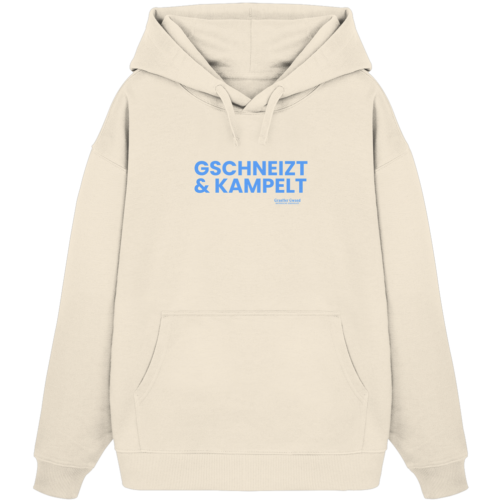Schwarzer Oversize-Hoodie mit blauem Frontprint „Gschneizt & Kampelt“. Moderner bayerischer Streetwear-Hoodie mit Dialekt-Motiv für Volksfest, Biergarten und Alltag. Extra schwerer Premium-Hoodie, designed und bedruckt in Bayern von Grantler Gwand.