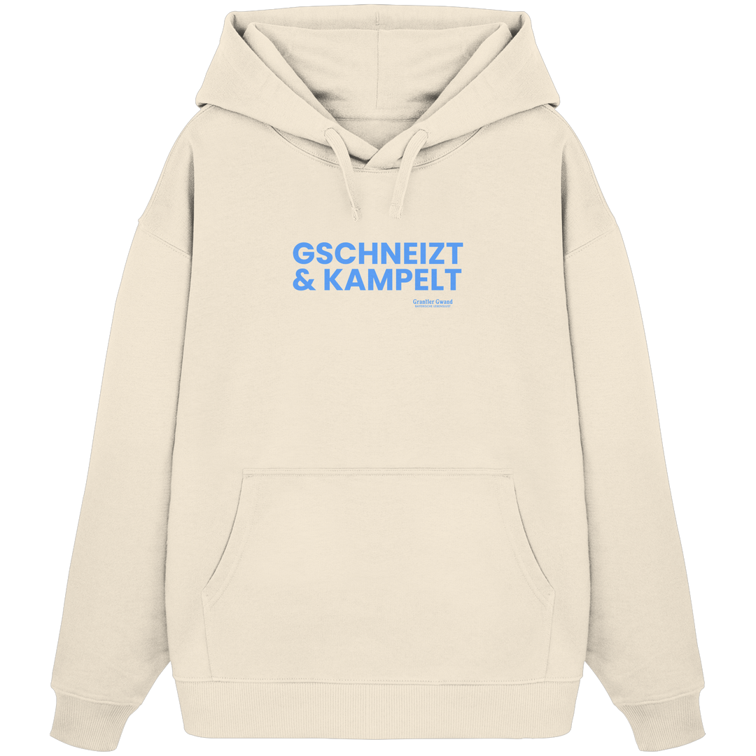 Schwarzer Oversize-Hoodie mit blauem Frontprint „Gschneizt &amp; Kampelt“. Moderner bayerischer Streetwear-Hoodie mit Dialekt-Motiv für Volksfest, Biergarten und Alltag. Extra schwerer Premium-Hoodie, designed und bedruckt in Bayern von Grantler Gwand.