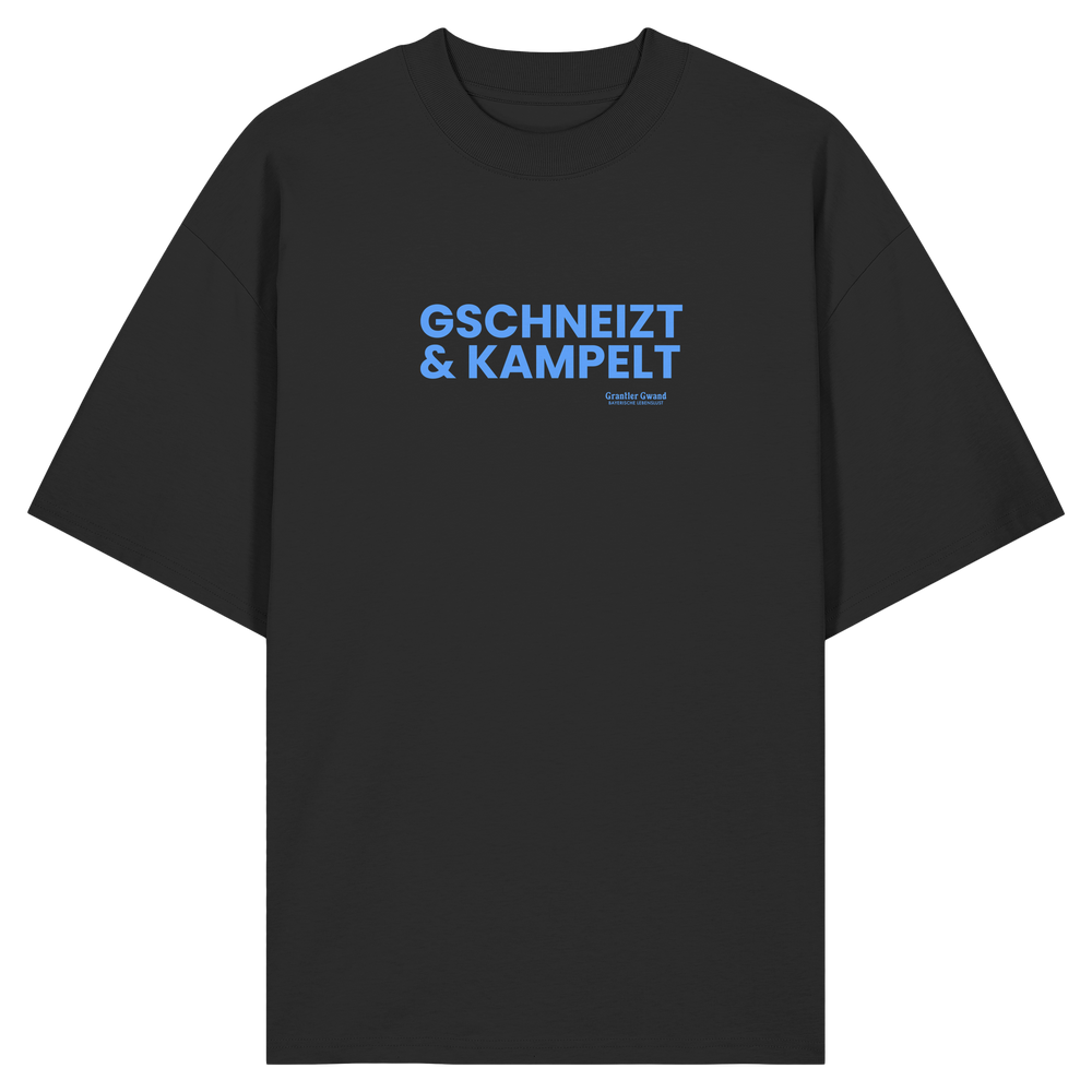 Schwarzes Oversize-T-Shirt mit blauem Frontprint „Gschneizt & Kampelt“. Modernes bayerisches Streetwear-Shirt mit Dialekt-Motiv für Volksfest, Biergarten und Alltag. Hochwertige Bio-Baumwolle, designed und bedruckt in Bayern von Grantler Gwand.