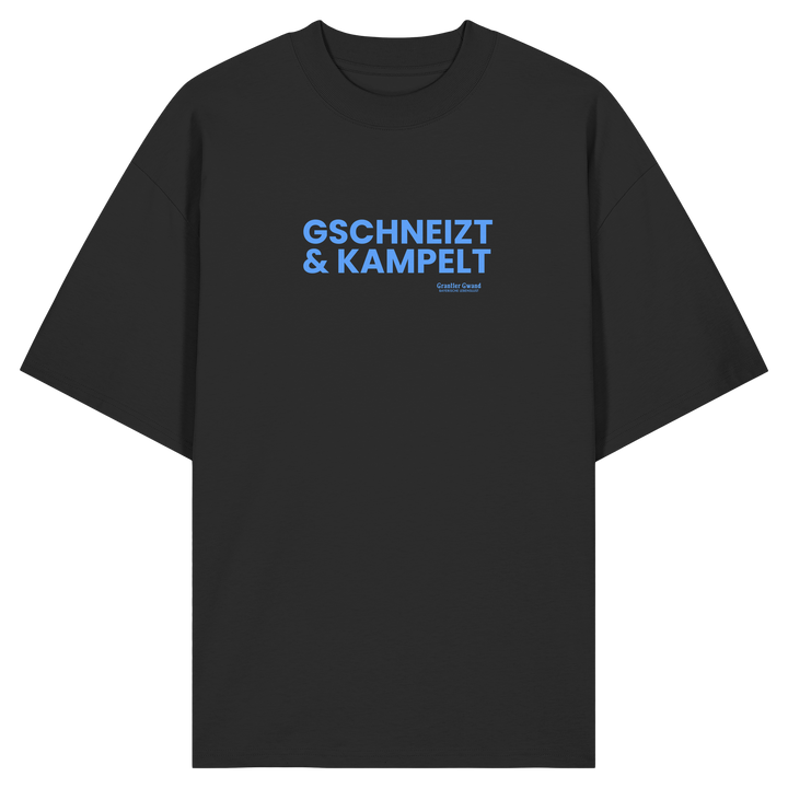 Schwarzes Oversize-T-Shirt mit blauem Frontprint „Gschneizt &amp; Kampelt“. Modernes bayerisches Streetwear-Shirt mit Dialekt-Motiv für Volksfest, Biergarten und Alltag. Hochwertige Bio-Baumwolle, designed und bedruckt in Bayern von Grantler Gwand.