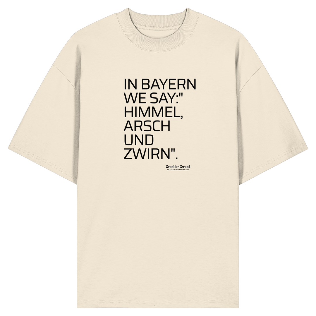 Naturfarbenes  Oversize Shirt mit schwarzem Schriftzug „In Bayern we say: Himmel, Arsch und Zwirn“ auf der Vorderseite von Grantler Gwand.
