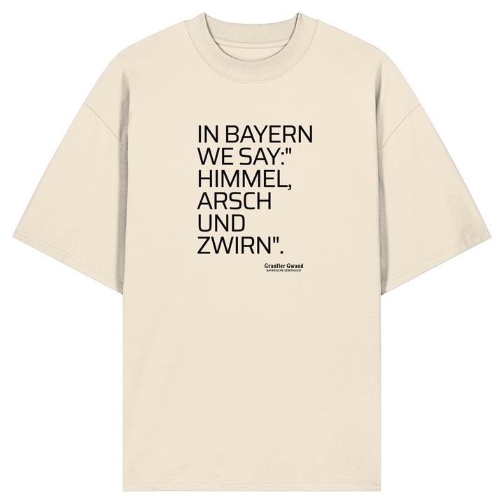 Naturfarbenes  Oversize Shirt mit schwarzem Schriftzug „In Bayern we say: Himmel, Arsch und Zwirn“ auf der Vorderseite von Grantler Gwand.