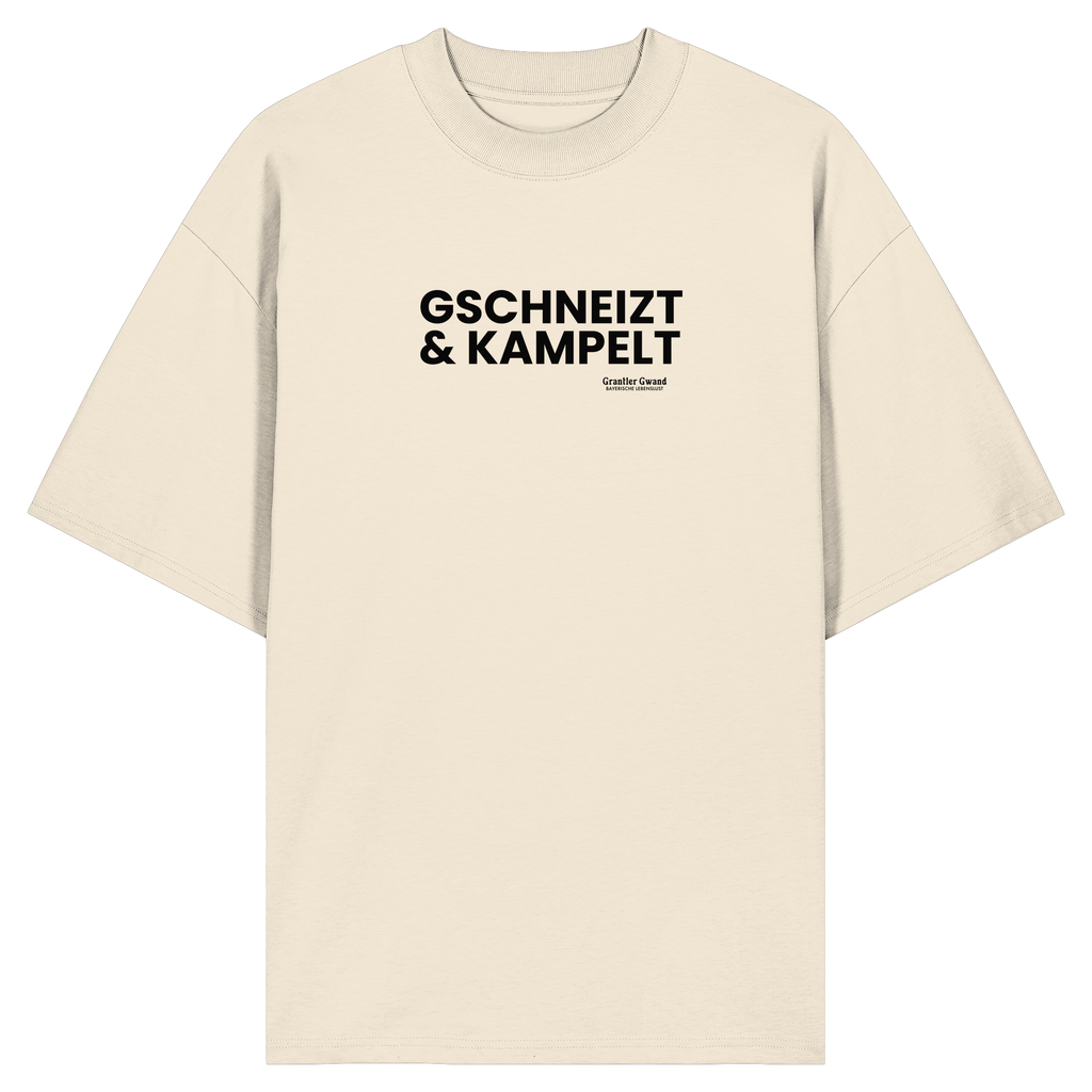 Beiges Oversize-T-Shirt mit schwarzem Frontprint „Gschneizt & Kampelt“. Modernes Unisex-Shirt mit bayerischem Dialekt im minimalistischen Streetwear-Design für Volksfest, Biergarten und Alltag. Hochwertige Bio-Baumwolle, designed und bedruckt in Bayern von Grantler Gwand.
