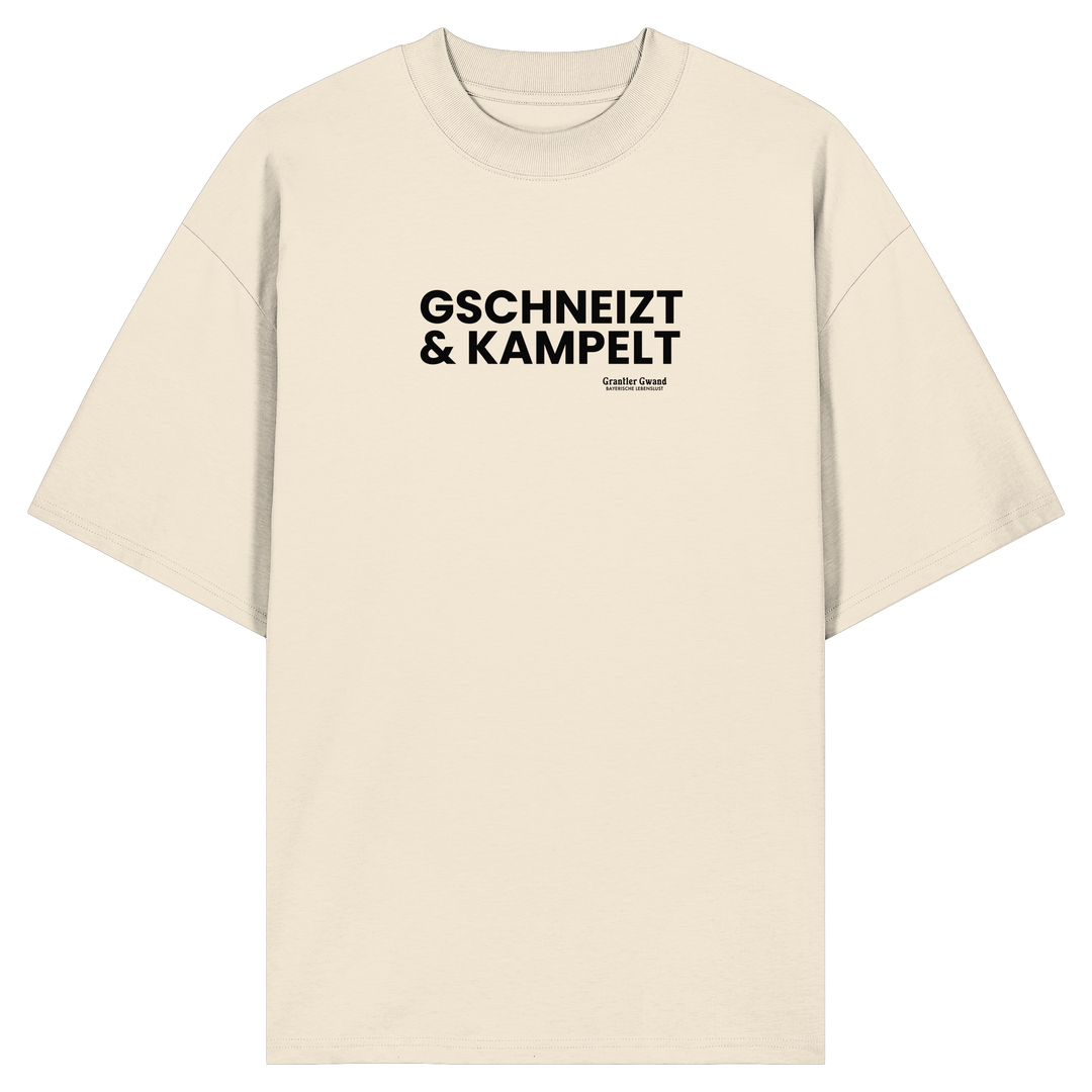 Beiges Oversize-T-Shirt mit schwarzem Frontprint „Gschneizt &amp; Kampelt“. Modernes Unisex-Shirt mit bayerischem Dialekt im minimalistischen Streetwear-Design für Volksfest, Biergarten und Alltag. Hochwertige Bio-Baumwolle, designed und bedruckt in Bayern von Grantler Gwand.