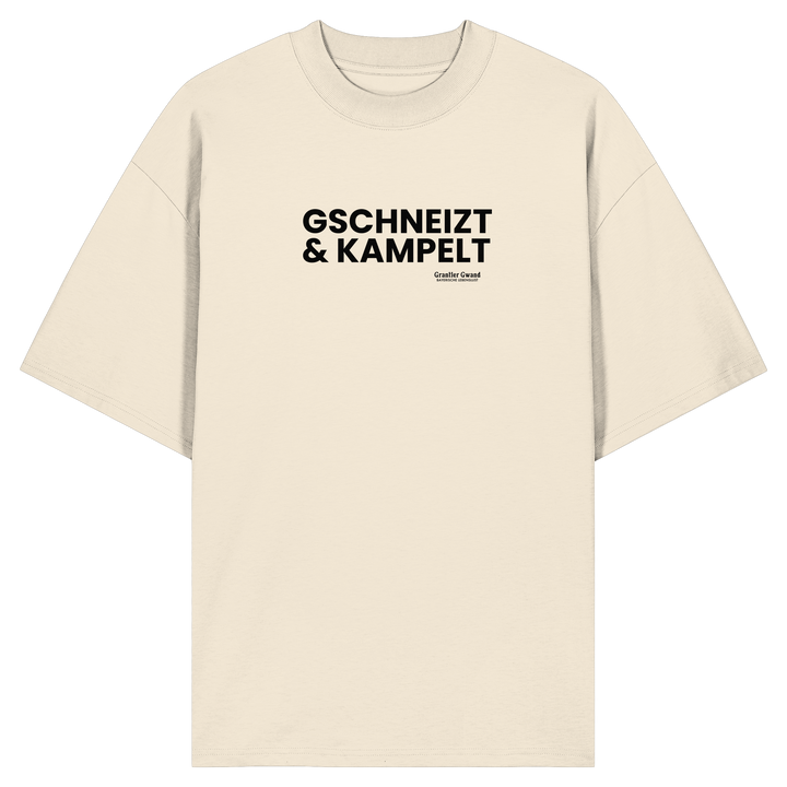 Beiges Oversize-T-Shirt mit schwarzem Frontprint „Gschneizt &amp; Kampelt“. Modernes Unisex-Shirt mit bayerischem Dialekt im minimalistischen Streetwear-Design für Volksfest, Biergarten und Alltag. Hochwertige Bio-Baumwolle, designed und bedruckt in Bayern von Grantler Gwand.