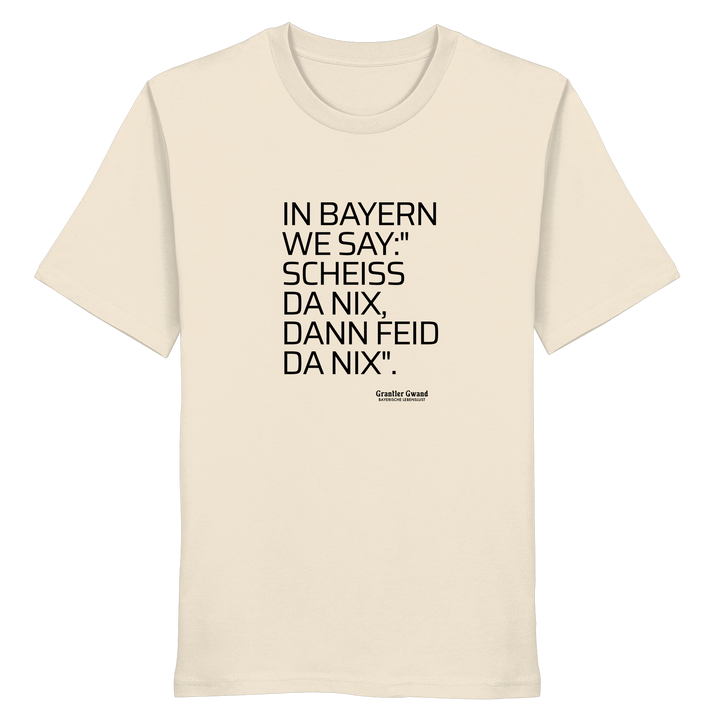 Naturfarbenes Shirt mit schwarzem Schriftzug "In Bayern we say: Scheiß da nix, dann feid da nix" im minimalistischen bayerischen Streetwear-Design von Grantler Gwand.